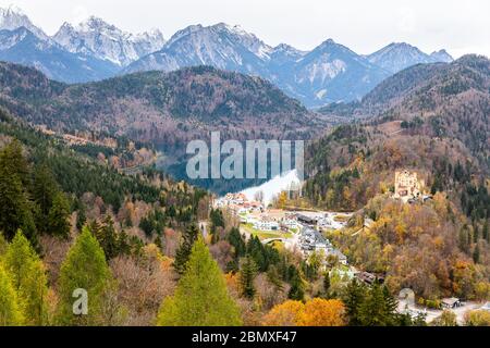 Luftaufnahme über den Alpsee und die ländliche Stadt, die im Herbst von Bergkette umgeben ist. Stockfoto