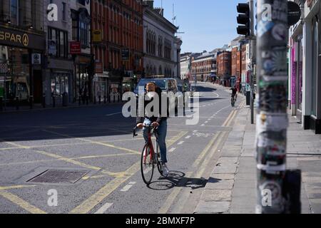 Ein Mann, der während der Coronavirus-Pandemie eine Gesichtsmaske trägt, geht entlang einer Straße in Dublin, Irland. Stockfoto