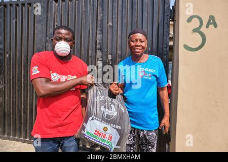 Ein Freiwilliger übergibt einer Frau während der Covid-19-Sperre in Lagos, Nigeria, eine Lebensmittelverpackung. Stockfoto