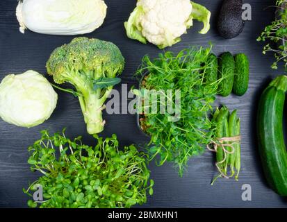 Vielfalt von grünem Gemüse auf Holzhintergrund, Brokkoli, Avocado, Mikrosprossen, Erbsen, Salat, Zuchini, Gurke, Blumenkohl, Kohl, flacher Lay. De Stockfoto