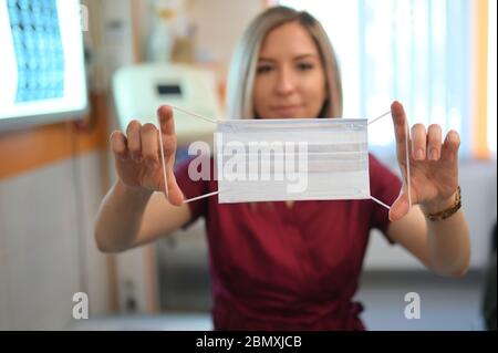 Junge Frau Doktor zieht eine Schutzmaske an Stockfoto