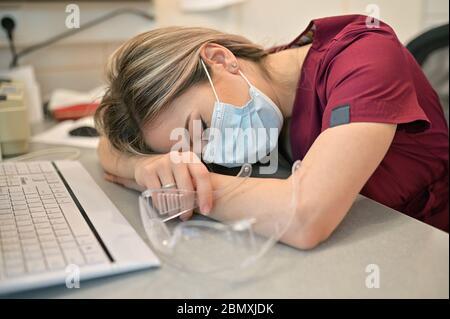 Junger Doktor, Der Auf Dem Schreibtisch Im Medizinischen Büro Schläft Stockfoto