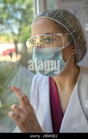 Junger Arzt erschöpft Blick aus Fenster Stockfoto