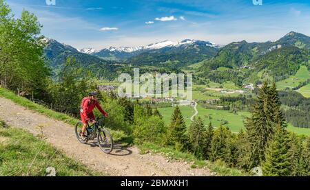 Eine hübsche ältere Frau, die mit ihrem Elektro-Mountainbike auf dem Wallraff-Trail im Nebelhorn oberhalb von Oberstdorf, Allgäu, Bayern, unterwegs ist. Stockfoto