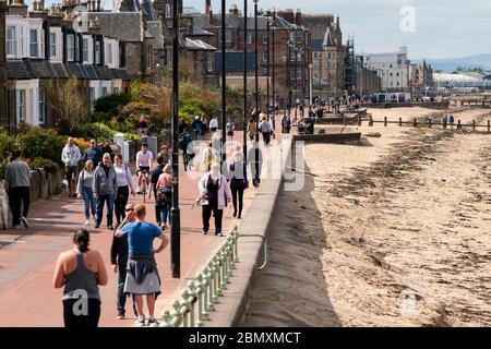 Portobello, Schottland, Großbritannien. 11 Mai 2020. Am späten Nachmittag Blick auf den beliebten Strand und die Promenade von Portobello. Trotz gelegentlicher Polizeikontrollen war die Öffentlichkeit entschlossen, sich zu entspannen und in der Sonne zu sitzen. Promenade voll mit Menschen zum Entspannen und Trainieren. Iain Masterton/Alamy Live News Stockfoto