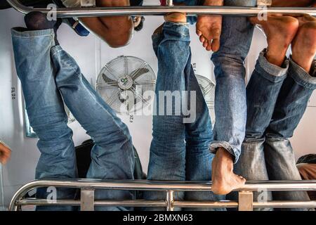 Low-Angle-Aufnahme einer Gruppe von Männern in Jeans, die in einem Zug im Gepäckraum sitzen, Indien Stockfoto