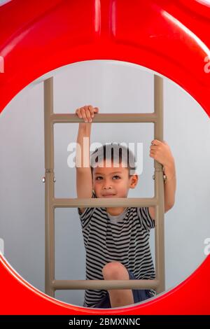 Portrait von asiatischen Jungen sind die Leiter in den Spielplatz. Stockfoto