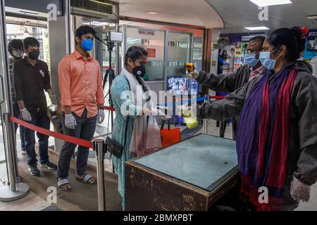 Dhaka, Bangladesch. Mai 2020. Ein Mitarbeiter gibt einer Frau am 11. Mai 2020 auf einem Markt in Dhaka, Bangladesch, Händedesinfektionsmittel. Am Montag waren die Hauptstraßen und Straßen Dhaka wieder voll, einen Tag nachdem die Geschäfte und Märkte nach einem Regierungsbefehl wieder eröffnet wurden, allerdings nur begrenzt. Kredit: Str/Xinhua/Alamy Live News Stockfoto