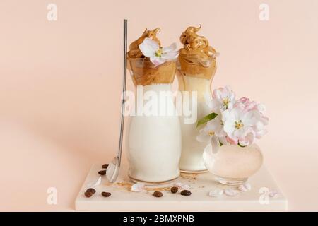 Trendy gepeitschten kalten Dalgona Kaffee im Glas mit Apfelbaumblumen Stockfoto