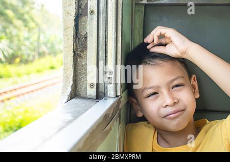 Portrait von asiatischen Jungen im Zug Hintergrund Fenster Aussicht und Bäumen. Stockfoto