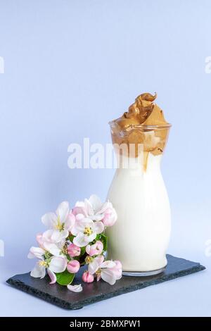 Trendy gepeitschten kalten Dalgona Kaffee im Glas mit Apfelbaumblumen Stockfoto