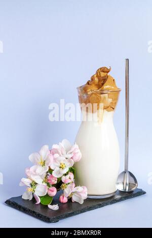 Trendy gepeitschten kalten Dalgona Kaffee im Glas mit Apfelbaumblumen Stockfoto