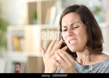 Erwachsene Frau mit Arthritis in Schmerzen berührt Gelenk in der Hand sitzen im Wohnzimmer zu Hause Stockfoto