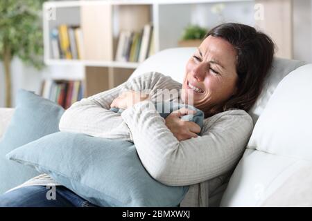 Traurige Erwachsene Frau weinend auf dem Sofa sitzend Kissen im Wohnzimmer zu Hause Stockfoto