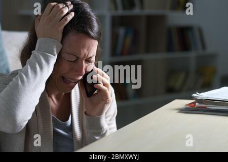Traurige Frau mittleren Alters weinend Anruf auf Smartphone sitzen auf dem Boden in der Nacht zu Hause Stockfoto