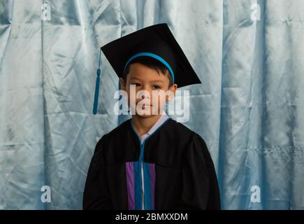 Der Junge hat den Kindergarten abgeschlossen. Diese Studie ist die erste, die auf die nächste Ebene vorrücken. Stockfoto