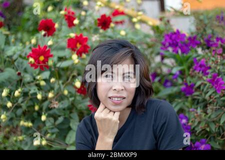 Portrait asiatische Frau mit roten Blumen und lila Blumen Stockfoto