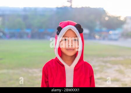 Asia Junge trägt einen roten Weihnachtshintergrund auf dem Rasen der Schule. Stockfoto