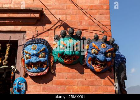 Kathmandu, Nepal - 13. November 2016: Souvenirshop in Kathmandu. Nepalesische traditionelle Dämonenmasken hängen an einer Ziegelwand eines Ladens. Stockfoto