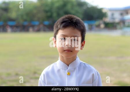 Porträt des asiatischen Jungen trägt ein weißes Hemd im Gras. Stockfoto