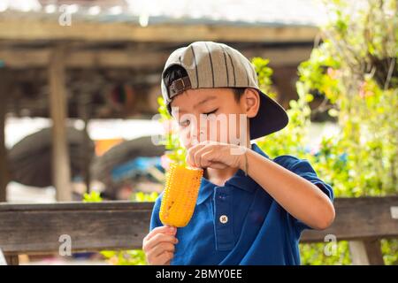 Asiatische junge essen gegrillten Mais. Stockfoto