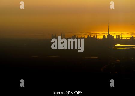 Unaufgerreges, kontrastreich schöne Luftaufnahme der Skyline von Dubai mit Blick über den Arabischen Golf bei Sonnenuntergang. Stockfoto