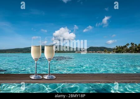 Luxus-Sommerurlaub Feier mit zwei Gläsern Champagner auf einem Tisch in der Lagune der Society Islands. Stockfoto