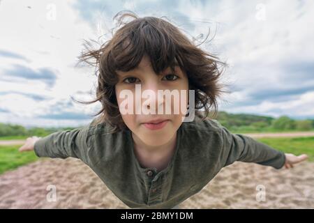 Freudiger Junge im Flug (Levitation-Effekt). Verzerrung eines Ultra-Weitwinkelobjektivs. Stockfoto