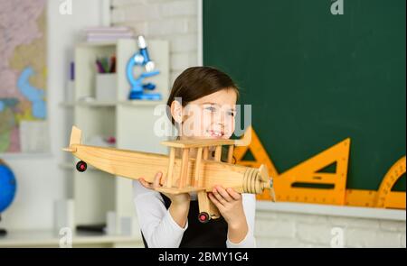 Wie ich den Sommer verbrachte. Anreise mit dem Flugzeug. Träumen Sie weiter. Schulmädchen spielen Holz Spielzeug Flugzeug. Fliegen Sie im Flugzeug. Studium der Geographie. Weltweit. Träume vom Reisen. Zurück zur Schule. Geschichte über Sommerferien. Stockfoto