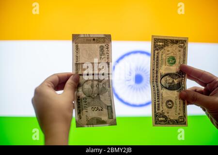 Hände, die einen amerikanischen Dollar der vereinigten Staaten von amerika und indische Rupie vor einer indischen Flagge halten, die den Wert vergleicht, während er schwankt Stockfoto