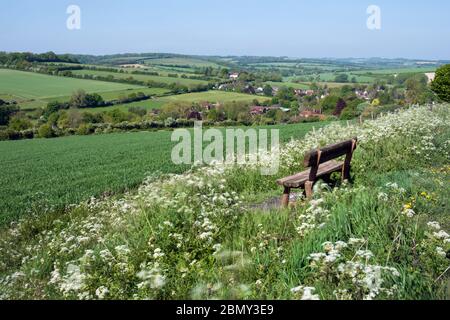 Holzbank mit Blick auf das Dorf East Garston und das Lambourn Valley, East Garston, West Berkshire, England, Großbritannien, Europa Stockfoto