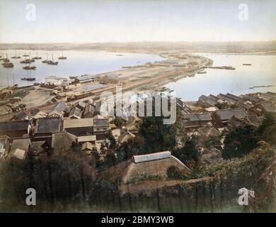 [ Japan 1870er - Japans erste Eisenbahn ] - EINE seltene Ansicht des brandneuen Bahnhofs Kanagawa (神奈川駅) auf der kürzlich fertiggestellten ersten japanischen Eisenbahn, die Yokohama mit Tokio verband, Anfang 1870er Jahre. Der Bau wurde 1870 begonnen (Meiji 3), und die Eisenbahn wurde am 12. Juni 1872 offiziell eröffnet (Meiji 5). Die Häuser im Vordergrund säumen die alte Tokaido-Autobahn in Kanagawa. Das bebaute Gebiet im Hintergrund ist Yokohama. Vintage Albumin-Fotografie aus dem 19. Jahrhundert. Stockfoto