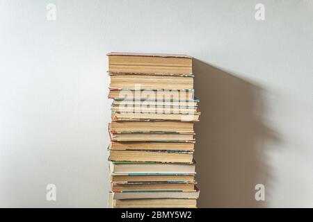 Großer Stapel alter Bücher über weißer Wand, Bildungskonzept, mit Kopierraum Stockfoto
