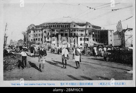 [ 1923 Japan - Erdbeben in Kanto ] - Evakuierte passieren nach dem Erdbeben in Kanto Daishinsai vom 1. September 1923 (Taisho 12) das verwüstete Kokugikan (両国国技館) im Bezirk Ryogoku (両国国技館) in Tokio. Die Kokugikan wurde 1909 eröffnet (Meiji 42) und war auch als Sumo Hall bekannt. Es wurde von dem berühmten Architekten Kingo Tatsuno (辰野金吾, 1854–1919) entworfen, der auch den Bahnhof Tokio (1914) und den Hauptsitz der Bank of Japan (1896) entwarf. Vintage-Postkarte des 20. Jahrhunderts. Stockfoto