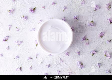 Weiße kosmetische Creme mit Blumen. Feuchtigkeitsspendende Creme für die Hautpflege. Gesundheit und Schönheit. Stockfoto