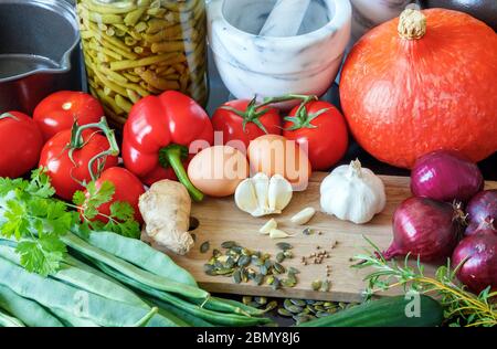 Zusammensetzung aus gesunder Gemüse, Kräutern, Gewürzen, Samen, Eiern und Kochutensilien. Stockfoto