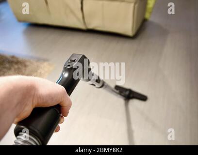 Mann Hand hält Staubsauger Rohr und macht Hausarbeit und saugen den Boden im Zimmer. Nahaufnahme aus Sicht der Person oder aus Sicht der ersten Person. Stockfoto