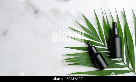 Nahaufnahme eines Paares schwarzer aromatischer Ölflaschen auf Palmblättern. Stockfoto