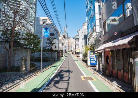 An einem sonnigen Frühlingstag liegt eine schmale Straße mit Wohngebäuden und Restaurants im Zentrum von Tokio Stockfoto