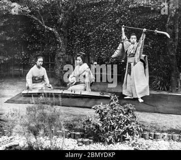 [ 1890er Jahre Japan - Japanische Frauen spielen Musik ] - zwei Frauen spielen die Shamisen und die Koto, während eine dritte mit einer Naginata tanzt, einer Polwaffe, die traditionell von Mitgliedern der Samurai-Klasse verwendet wird. Aus einer Serie von Glasdias, die vom schottischen Fotografen George Washington Wilson (1823–1893) veröffentlicht (aber nicht fotografiert) wurden. Wilsons Firma war einer der größten Verleger von Fotodrucken in der Welt. 19. Jahrhundert Vintage Glas Rutsche. Stockfoto