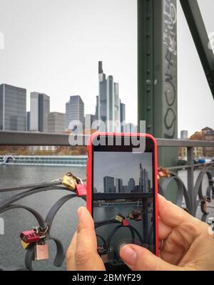 Nahaufnahme des Handydisplays und einer Hand, die ein Bild der Skyline von Frankfurt Main, Deutschland, komponiert Stockfoto