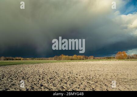 Riesige dunkle Hagel Wolke über dem gepflügten Feld, Blick auf einen Frühlings sonnigen Tag Stockfoto