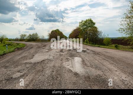 Extrem schlechte Asphaltstraße. Schlechte Qualität gefährliche Straße in der Ukraine. Gefahr von Reparatur von Autos und Reifen. Stockfoto