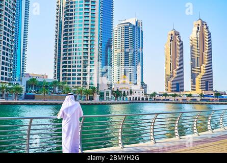 DUBAI, VAE - 2. MÄRZ 2020: Der Emirati, getragen in traditioneller weißer Kandura (thobe) und Ghutra (Kopftuch), steht am Baluster der Dubai Marina Stockfoto