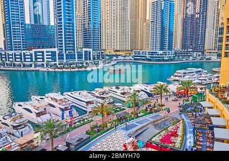 DUBAI, VAE - 2. MÄRZ 2020: Das hölzerne Touristenboot schwimmt am 2. März in Dubai an den Wolkenkratzern und vertäuten Yachten der Dubai Marina entlang Stockfoto