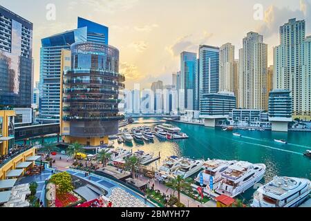 DUBAI, VAE - 2. MÄRZ 2020: Der goldene Sonnenuntergang über dem Pier 7 Gebäude und Yachten in der Marina Mall, umgeben von Luxus-Wohnhochhäusern, modern Stockfoto