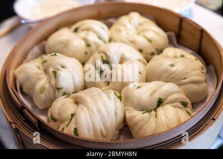 Chinesische Dim Sum gedünstete Frühlingszwiebeln Brötchen serviert in einem Bambusdampfer. Dim Sum ist eine einzigartige kulinarische Kunstform, die mit der Dose entstand Stockfoto