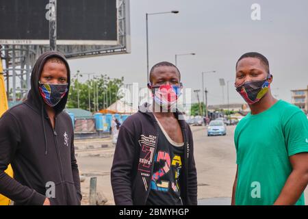 Drei Freunde, Ramsy, Michael und Dayo, posieren für ein Foto, während sie ihre ankara Gesichtsmasken in Lagos, Nigeria schaukeln. Die meisten Menschen jetzt Paar ihre Outfits w Stockfoto