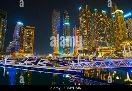 DUBAI, VAE - 2. MÄRZ 2020: Der Abendspaziergang entlang des Yachtclubs der Dubai Marina, umgeben von hell erleuchteten Türmen, am 2. März in Dubai Stockfoto