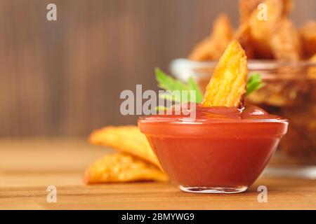 Frische knusprige Kartoffelspalten in Glasschüssel mit Ketchup. Kopierbereich. Stockfoto